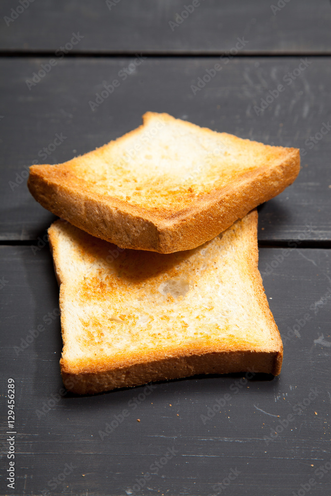Fototapeta premium Toast the bread on a black wooden background