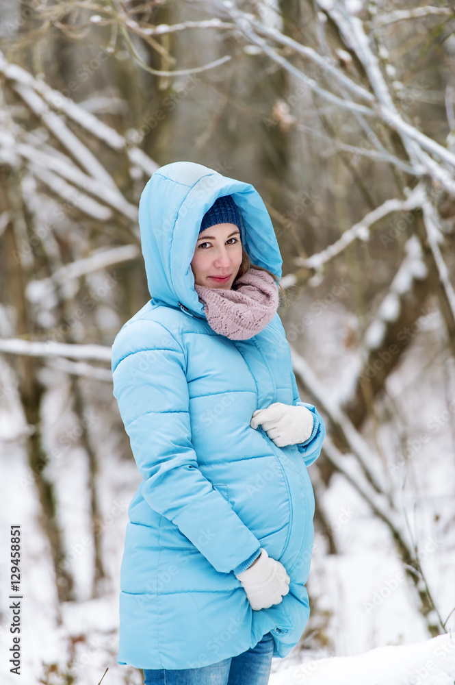 Portrait of the young pregnant woman in the winter park