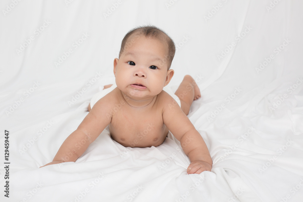 smiling surprised baby lying on a white bed. Baby born in Thailand, Asia. Infants aged 5 months smiling surprised baby lying on a white bed. Baby born in Thailand, Asia. Infants aged 5 months