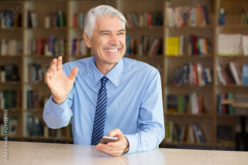 Fotografie Ironic senior man with cheesy grin waving hand