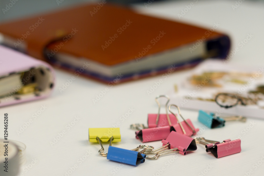 Fototapeta premium Notebooks in hand and colorful binders on the table. Glass full of pens and pencils, colored decorative tape.