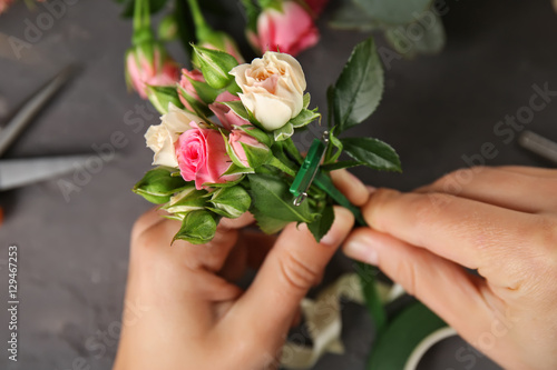 Female hands making beautiful bouquet of flowers on dark background