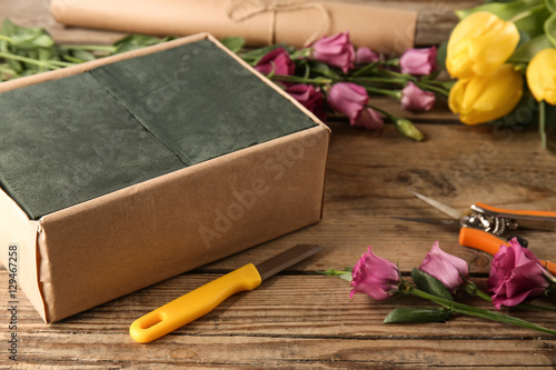 Beautiful flowers with box and florist equipment on wooden background