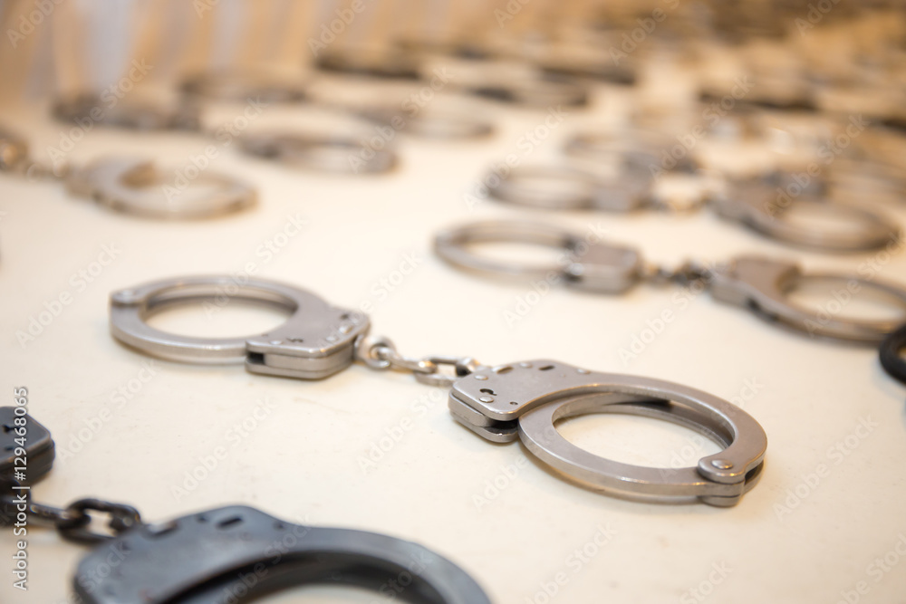 row of law enforcement silver metal handcuffs on white table row of law enforcement silver metal handcuffs on white table