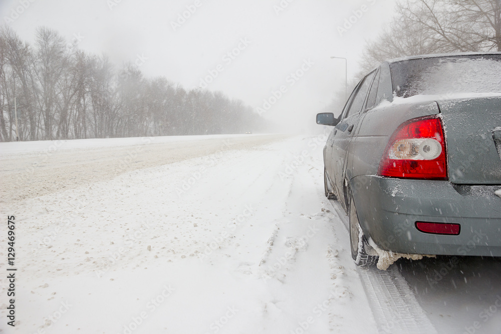 Car on winter road in a snowstorm and bad visibility