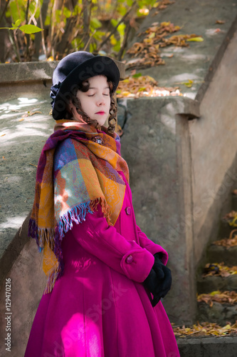 Fotografie Portrait girl in a bright crimson coat with eyes closed.