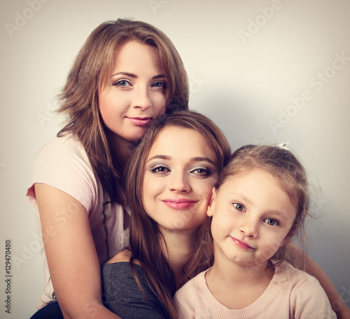Two young beautiful smiling women and happy kid girl hugging wit