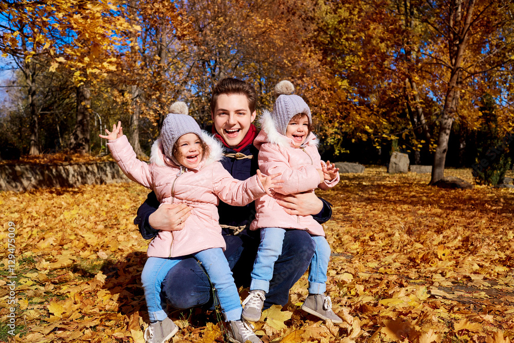 Happy children with father in the park autumn outdoors, yellow leaves laughing, having fun, smiling clothing

