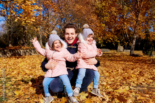 Happy children with father in the park autumn outdoors, yellow leaves laughing, having fun, smiling clothing 