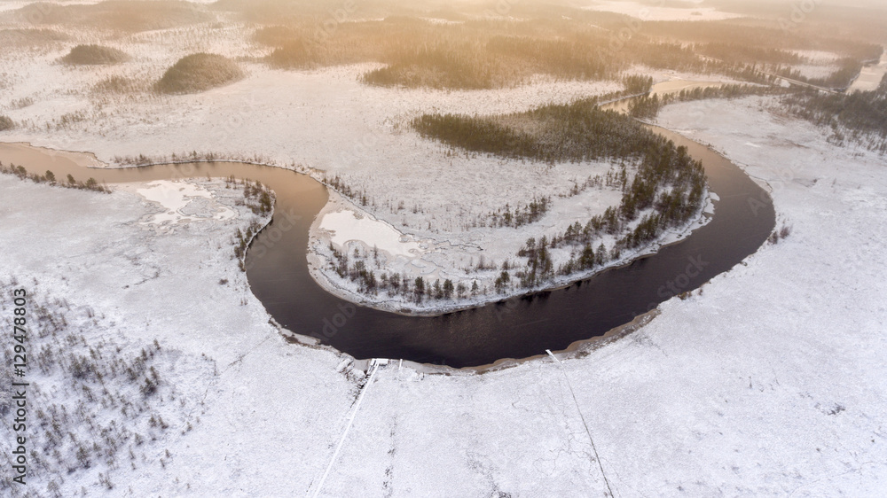 Aerial view at wintry river turn with open water and snow covered shores and swamps. Forests of Karelia, Russia.