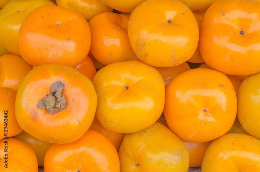 Organic persimmon fruits in pile at local farmers market Organic persimmon fruits in pile at local farmers market