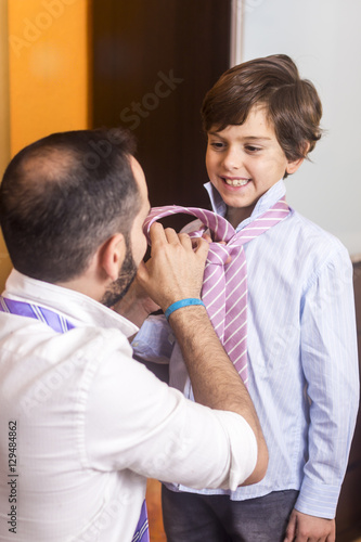 Father is helping his son to wear the tie.