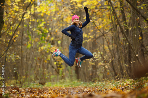 Sportswoman running among autumn leaves