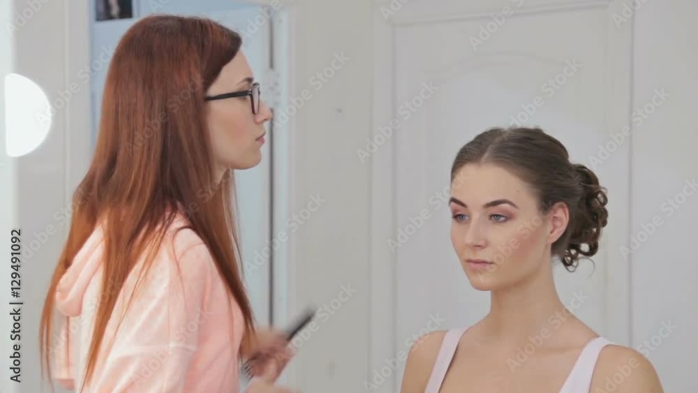 Hair stylist, hairdresser finishing hairstyle for young pretty woman and using hair spray in white make up room. Beauty and haircare concept Hair stylist, hairdresser finishing hairstyle for young pretty woman and using hair spray in white make up room. Beauty and haircare concept