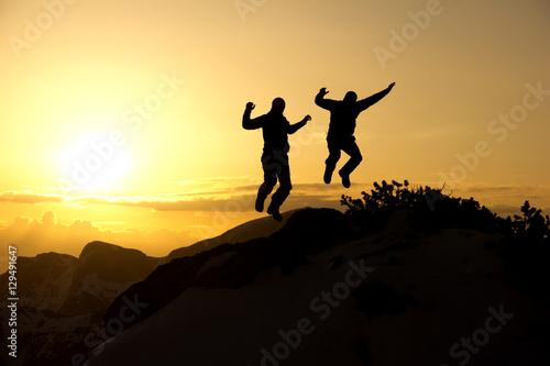 Enjoying summit/Two men happily jumping on the top of the mountain