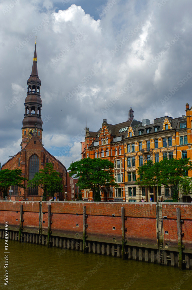 Hamburg, Germany - July 18, 2016: Warehouse District could Speicherstadt, with old Church on the elb river at cloudy day.