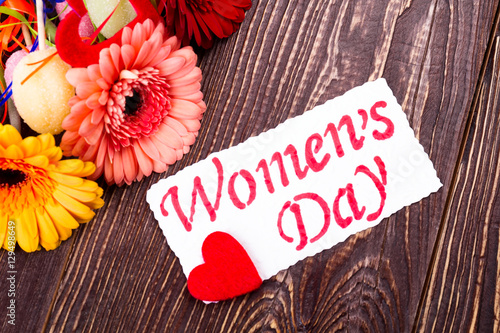 Women`s Day card with heart. Greeting paper near gerbera. Celebrate and give presents. Flowers and sweets for women.