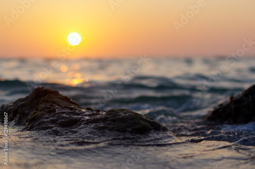 sea wave close up at sunset time with red and orange sun reflection on the water. nature abstract blurred background. Phuket island, Thailand