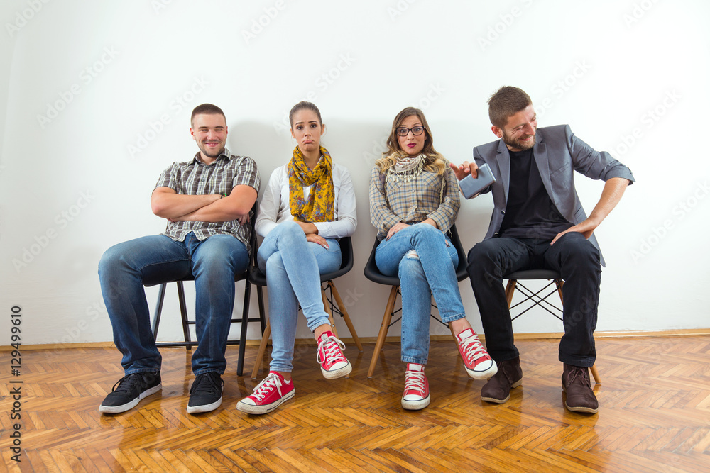 Fototapeta premium Group of young people is sitting in a row in an office lobby and waiting for the job interview.