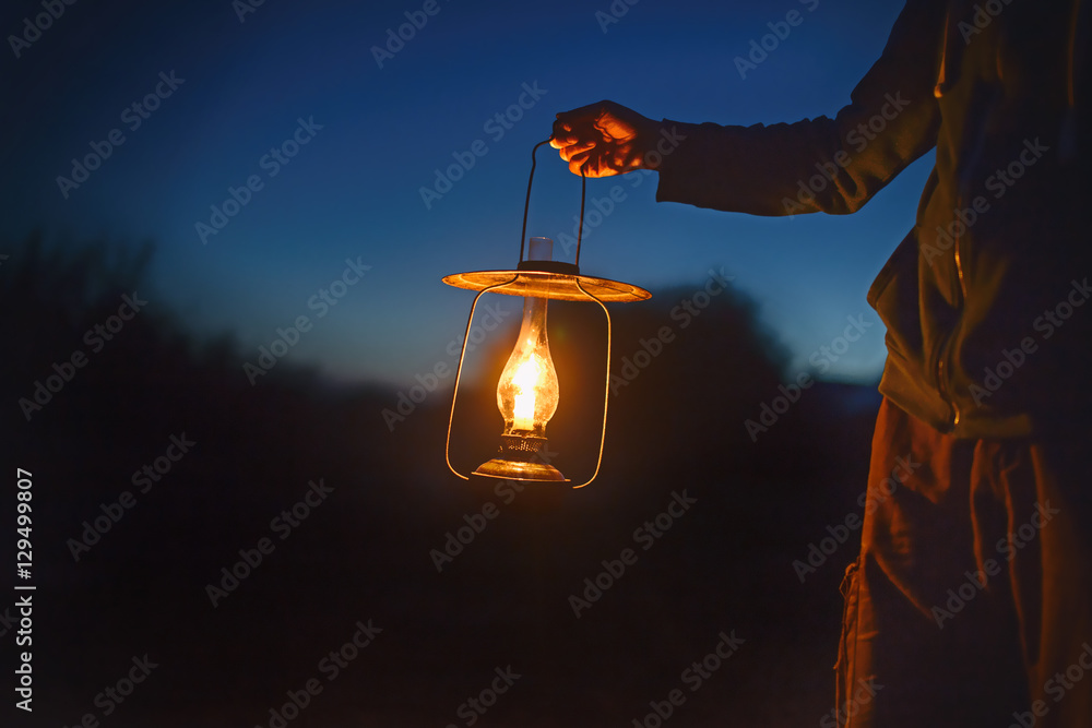 man holding the old lamp with a candle outdoors. hand holds a large lamp in  the dark. ancient lantern with a candle illuminates the way on a night  Stock Photo | Adobe