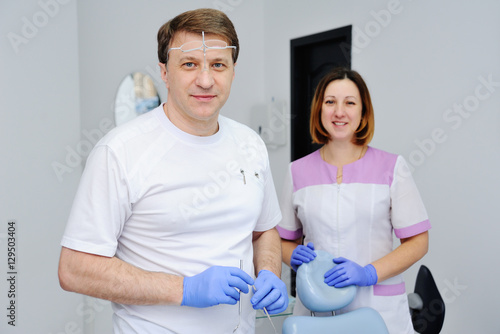 Male dentist with assistant medical instruments and girl on the background of the clinic