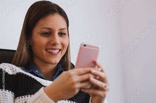 Happy young woman using her smart phone in her home office