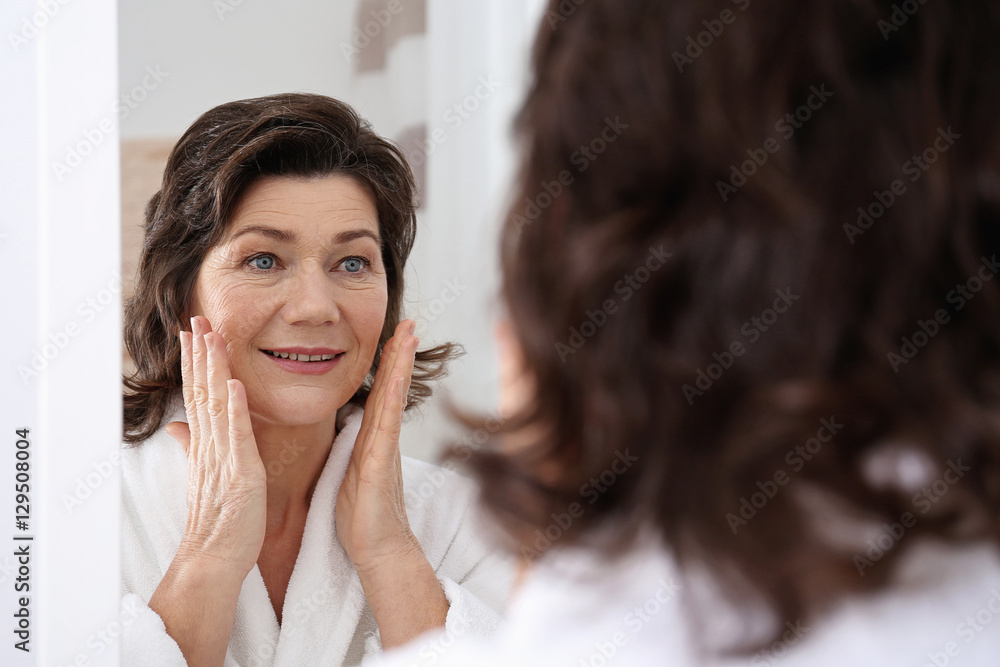 Senior woman touching face in front of mirror, closeup Senior woman touching face in front of mirror, closeup