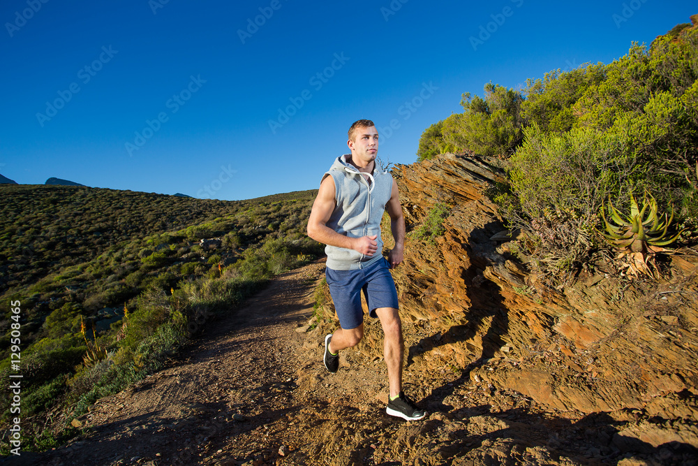 Male cross country athlete running in the hills on a warm and su