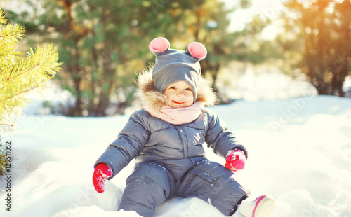 Winter happy smiling child playing in snow at sunny warm day