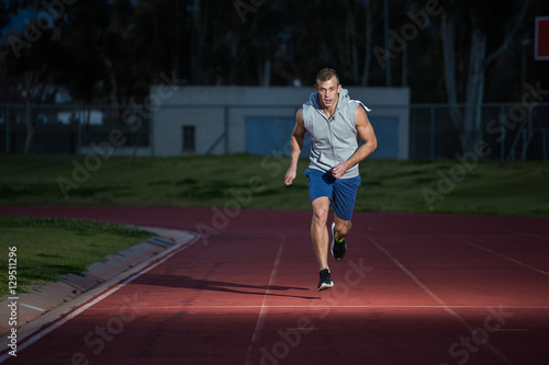 Male sprinter athlete on a tartan athletic track getting ready f