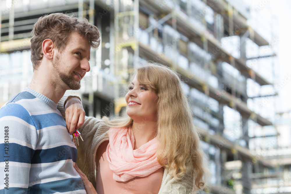 Couple with keys on front of new modern house