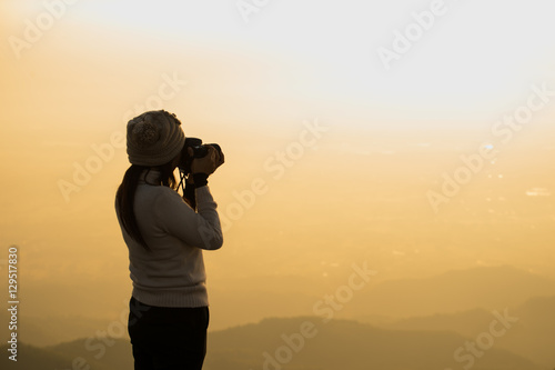 Silhouette of photographer taking picture of landscape during sunset, soft and select focus.