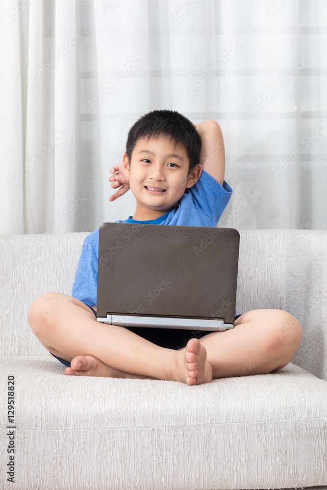 Happy Asian Chinese little boy using laptop on the sofa Happy Asian Chinese little boy using laptop on the sofa