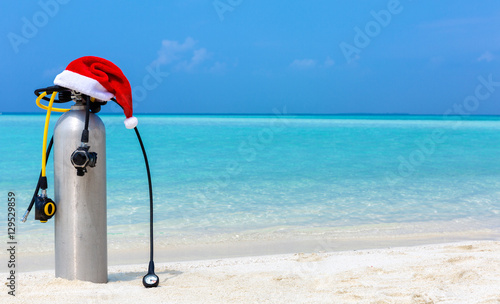 Taucherflasche mit Weihnachtsmütze am tropischen Strand