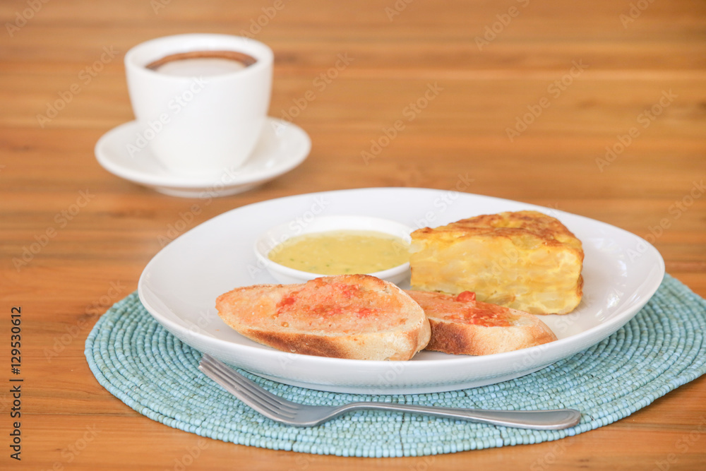 Spanish potato tortilla, bread and sauce served on the plate with a cup of coffee aside
Spanish potato tortilla, bread and sauce served on the plate with a cup of coffee aside