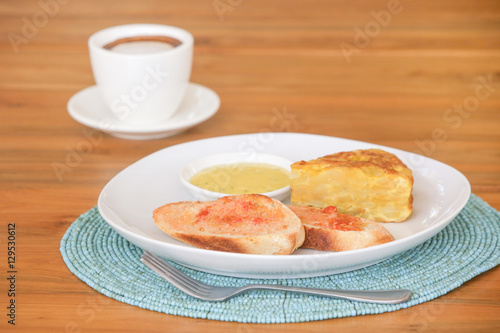 Spanish potato tortilla, bread and sauce served on the plate with a cup of coffee aside 