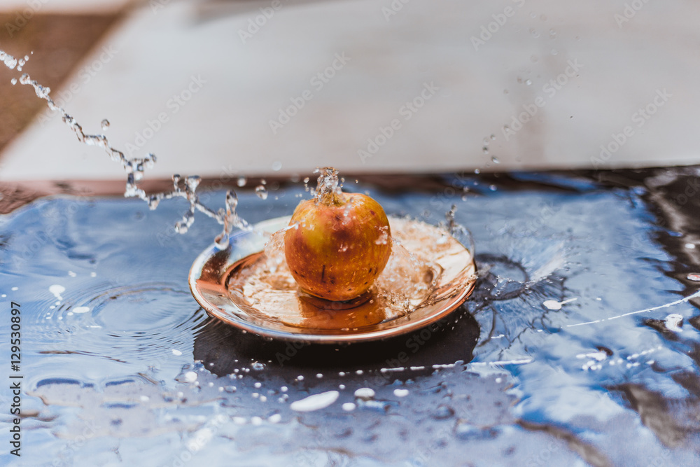 Fototapeta premium apples in the water stream standing on the plate outdoors