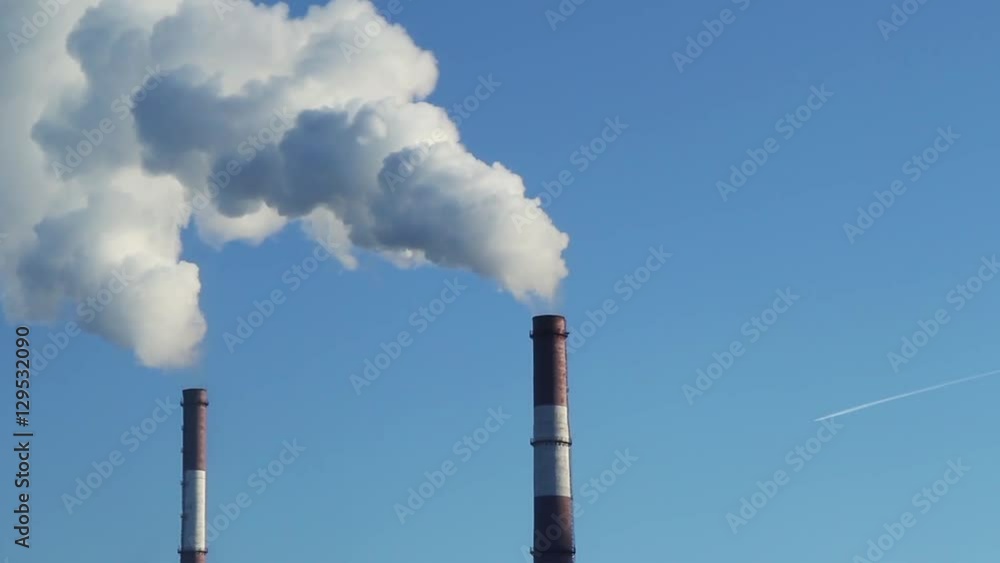 Industrial smoke from pipes against the blue sky Industrial smoke from pipes against the blue sky