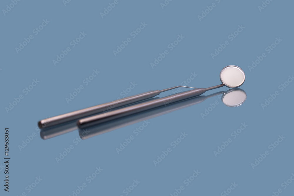 Dental mirror and dentist probe. Image isolated on blue background Dental mirror and dentist probe. Image isolated on blue background