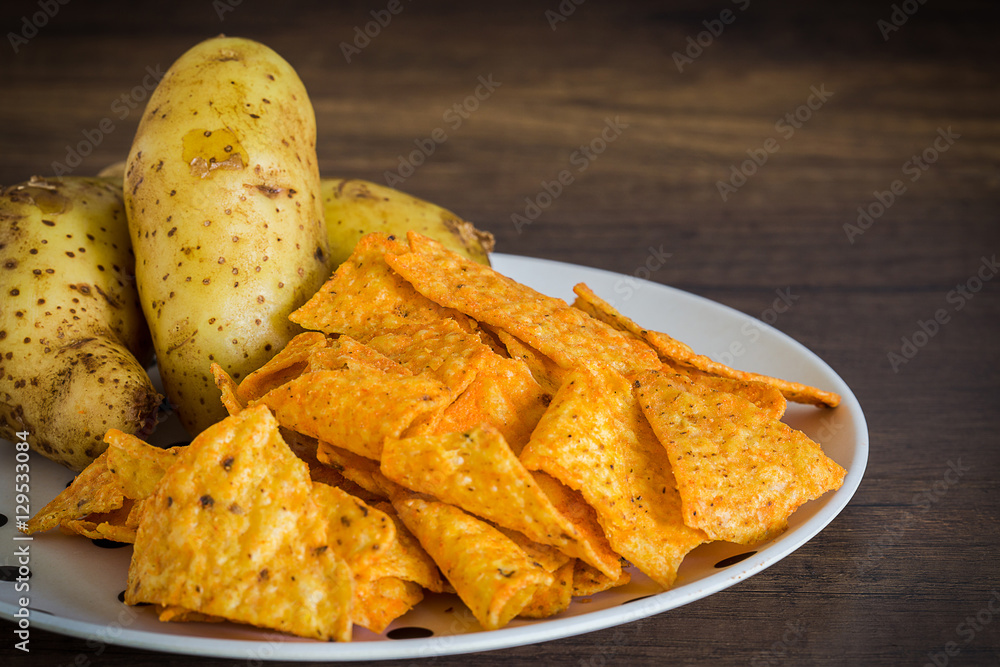 Corn chips with potatoes on the table with nature light in low key tone. Corn chips with potatoes on the table with nature light in low key tone.