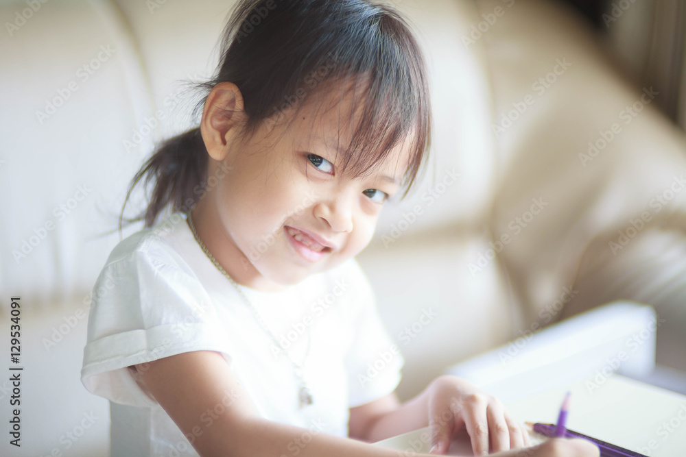 Cute asian child girl writing homework at sofa.Hi key style and Cute asian child girl writing homework at sofa.Hi key style and