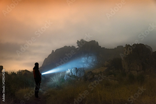 Man with a flashlight at night standing on mountains photo