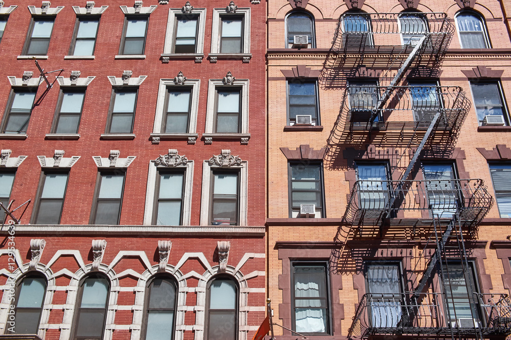 Obraz premium Brown and red brick building facades in, New York, with outside fire escapes and room air conditioners
