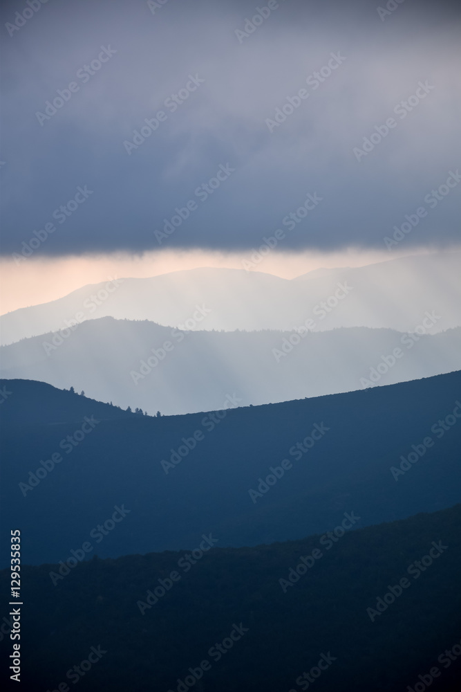 Layered mountain slopes and clouds in blue shades