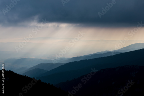 Layered mountain slopes and clouds in blue shades