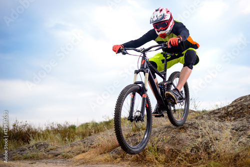 Fototapeta Naklejka Na Ścianę i Meble -  Professional Cyclist Riding the Bike Down Rocky Hill. Extreme Sport. Space for Text.