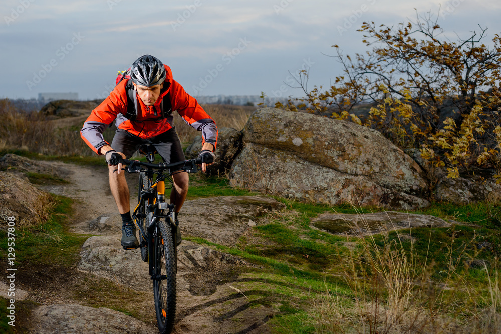 Cyclist in Red Jacket Riding the Bike on the Rocky Trail. Extreme Sport. Space for Text. Cyclist in Red Jacket Riding the Bike on the Rocky Trail. Extreme Sport. Space for Text.