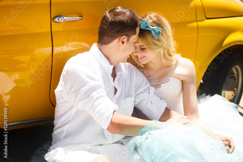 Bride with turquoise bow in her hear leans to groom sitting befo