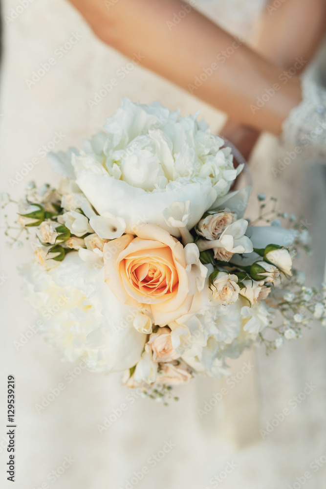 Bouquet of orange roses and large white flowers held by bride