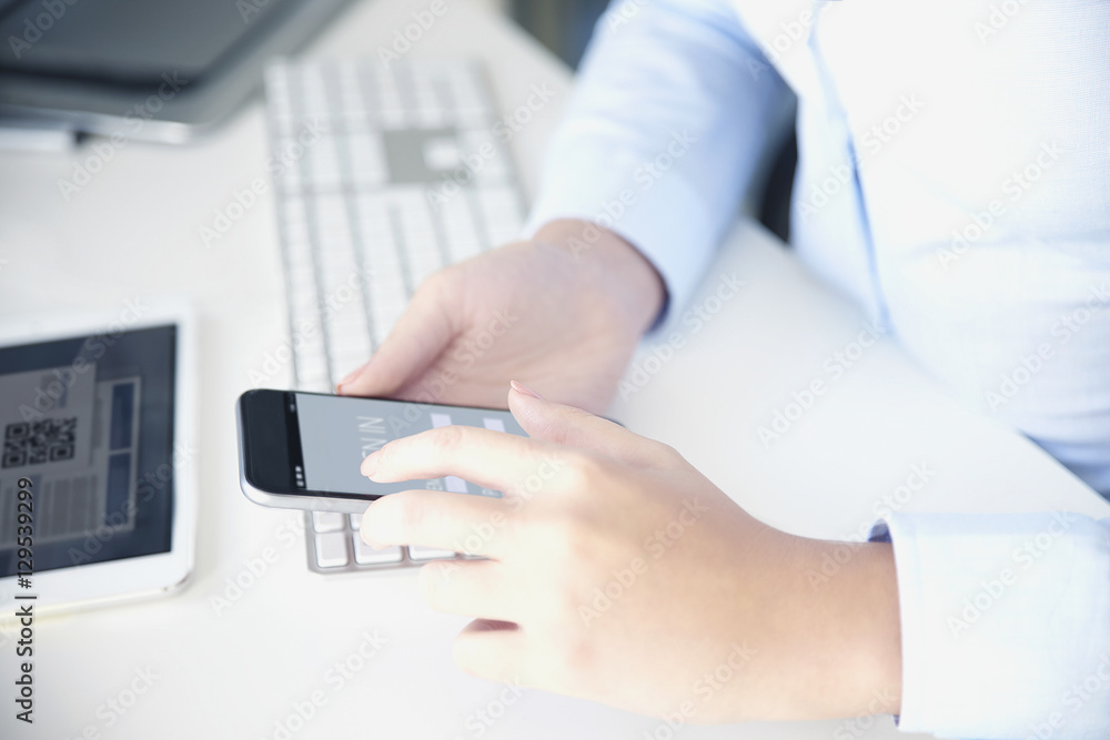 Fototapeta premium Private banking. Close-up shot of a businesswoman sitting at office in front of computer and using cellphone while banking online. 